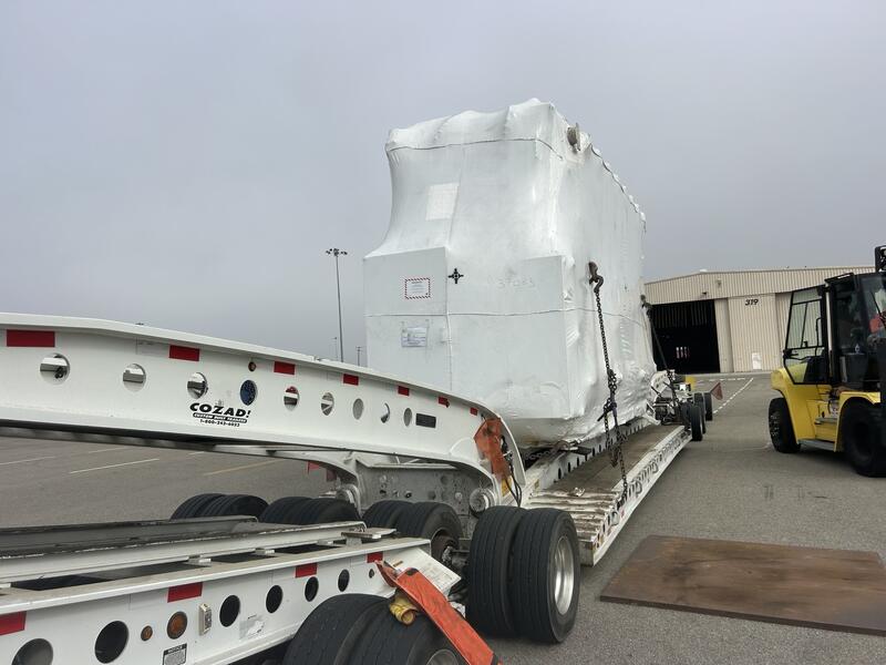 Shrink wrapped power transformer loaded on a Cozad lowboy heavy haul trailer at the terminal yard