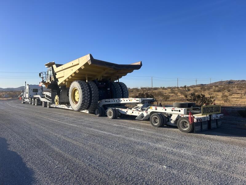 Oversize load mining haul truck secured on a multi axle removable gooseneck trailer with oversize load banner