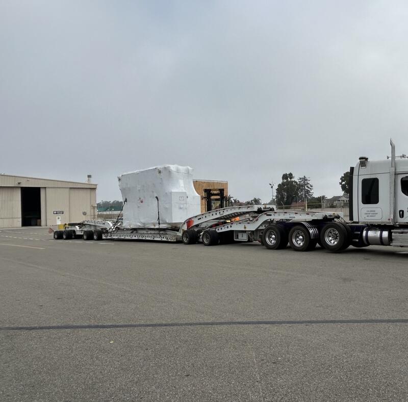 Heavy haul tractor and lowboy trailer staged with the wrapped power transformer before departure