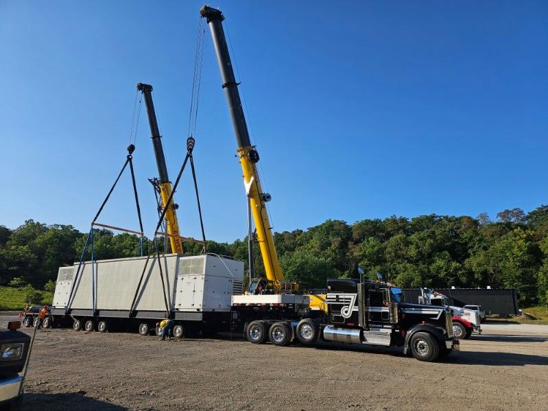 Two mobile cranes rigging the mission critical data center module during crane assisted loading onto the heavy haul trailer